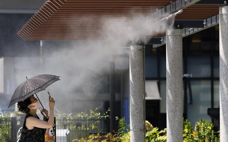 日本多个城市昨天的气温突破40摄氏度，东京银座的行人必须站在水汽喷雾下感受些许凉意。（彭博社）