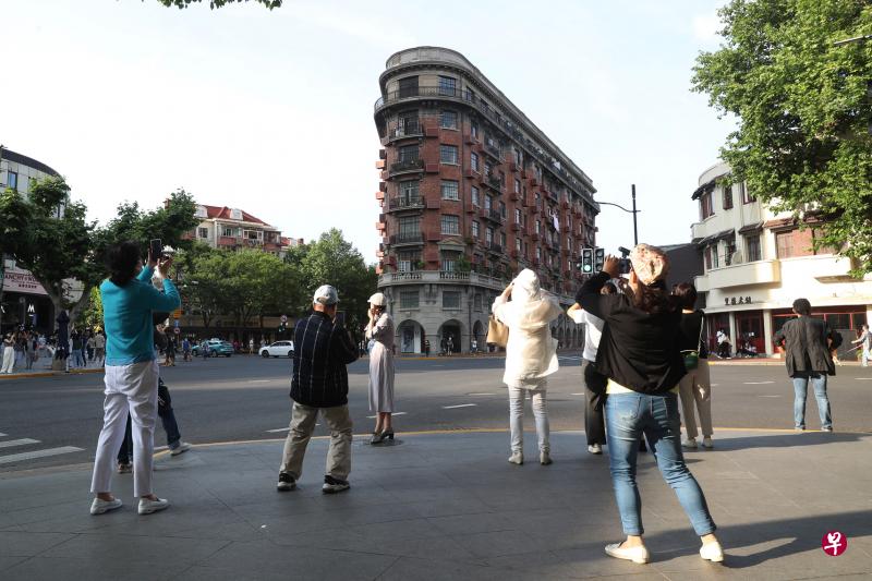 上海加速解封脚步，市民前天在武康大楼前“打卡”留念，附近街上也逐渐恢复往日气息。 （中新社）
