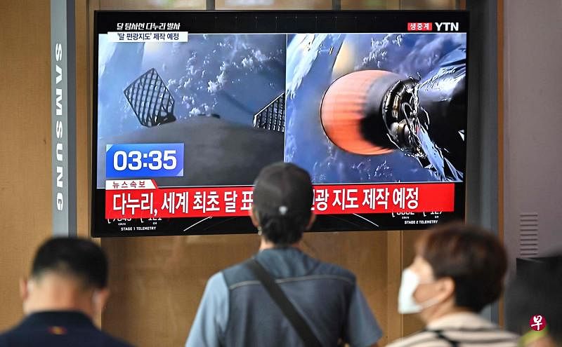 首尔地铁站的电视屏幕播放韩国首个月球轨道探测器发射的画面，吸引民众驻足观看。（法新社）