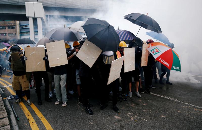 香港示威者以木板和雨伞当盾牌,抵抗警察发射的催泪弹(路透社)