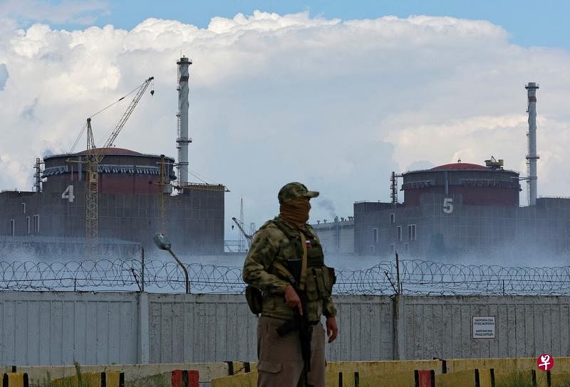 俄罗斯于3月占领了乌克兰扎波罗热州的这座核电站。一名穿着印有俄罗斯国旗的军人在核电站外守卫。（路透社） 